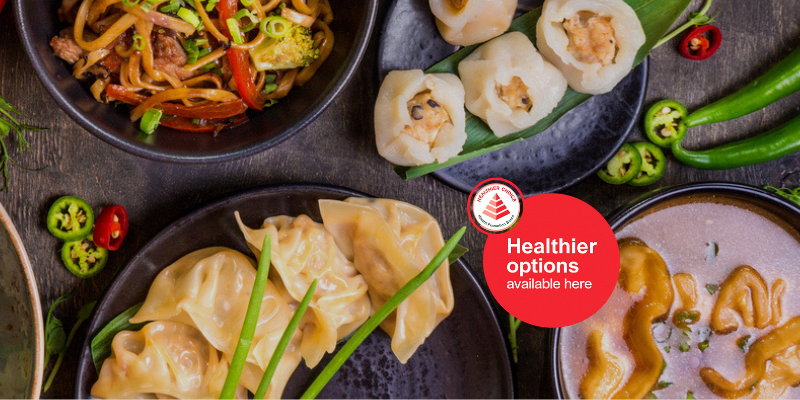 Assorted Asian dishes including dumplings, noodles, and vegetables on dining table.